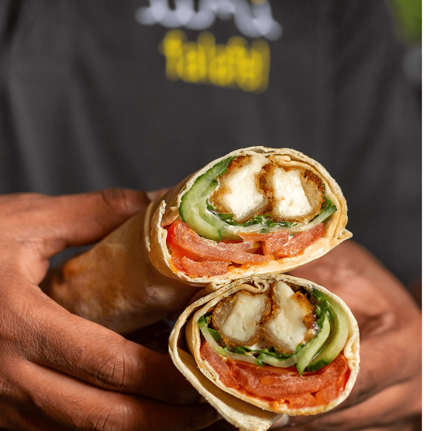 The breaded halloumi wrap cut in half, showing halloumi, tomato and cucumber