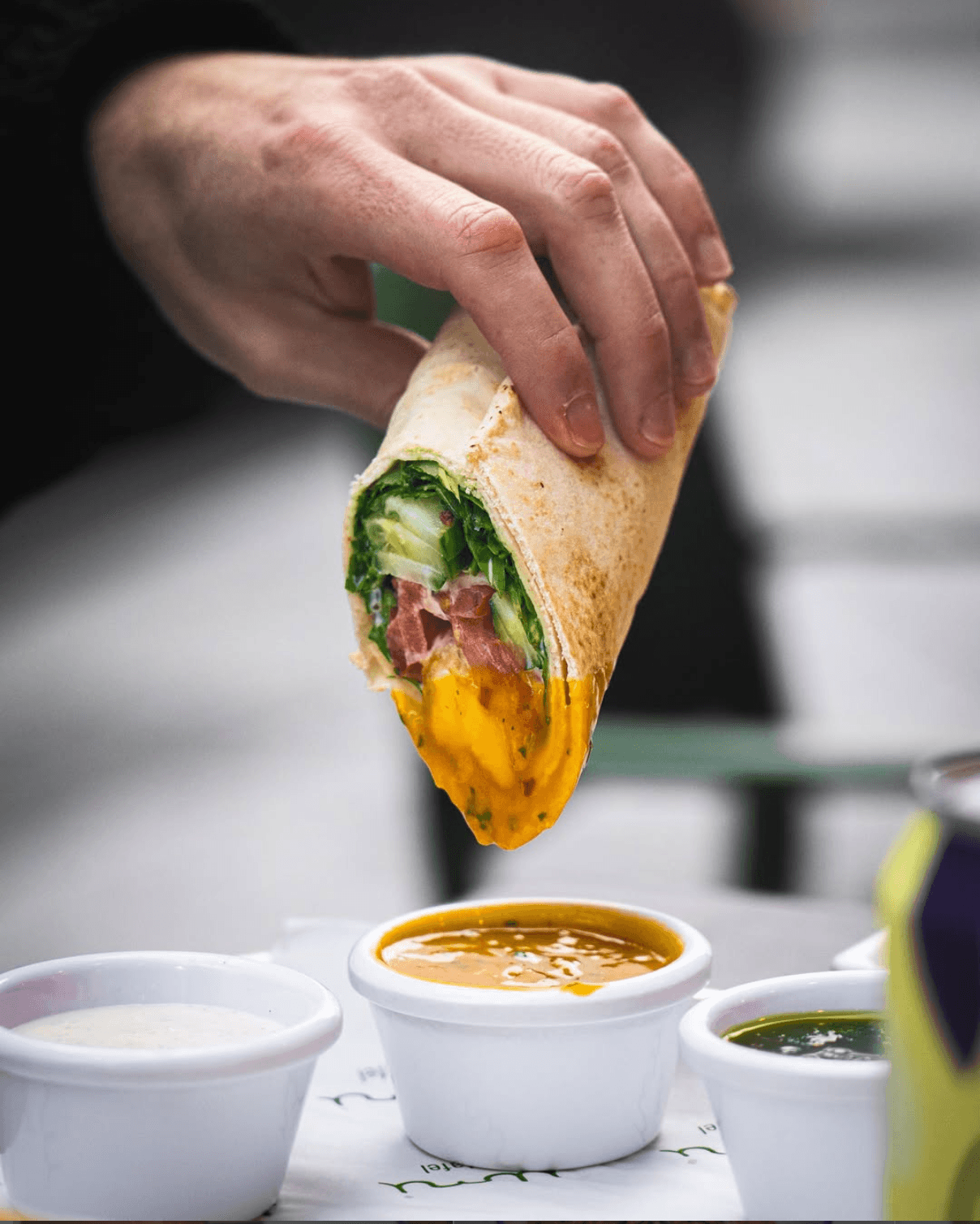 A falafel wrap being dipped into Umi's mango sauce